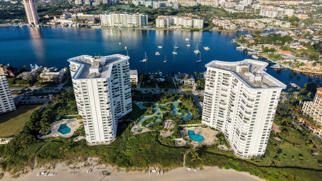 Drone view of the Chalfonte condo towers in Boca Raton, Florida, with Lake Boca Raton, boats, and downtown buildings behind them.